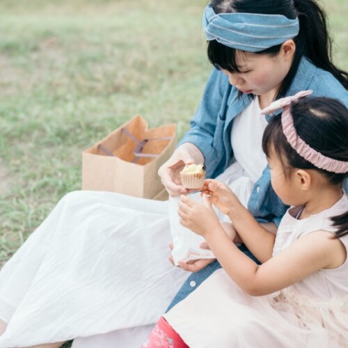 ピクニックで菓子を食べる親子