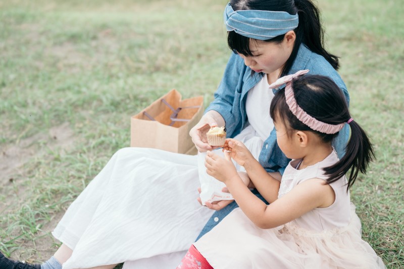 ピクニックで菓子を食べる親子
